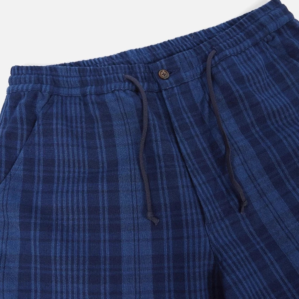 Le pantalon hi water indigo plaid par universal works possède une nouvelle coupe loose et plus courte laissant apparaître la cheville pour une silhouette décontractée. Cette coupe est idéale pour le printemps/été.